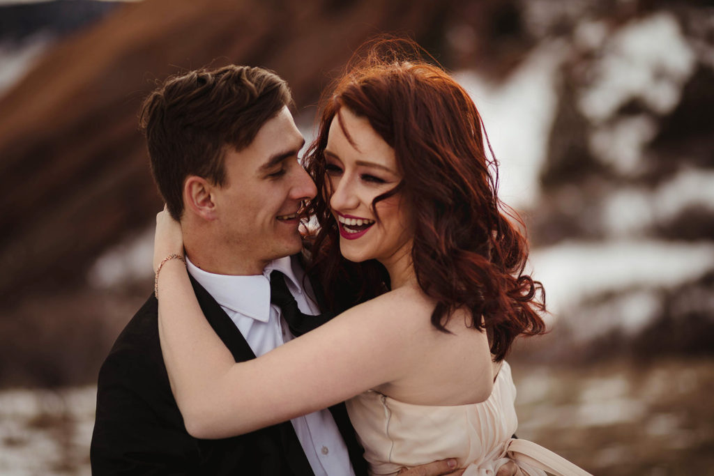 Wedding Professional Photographer in Denver, Colorado. Beautiful bride and groom in a professional photo session ,beautiful bride smiling to the groom and hugging him on the mountain view